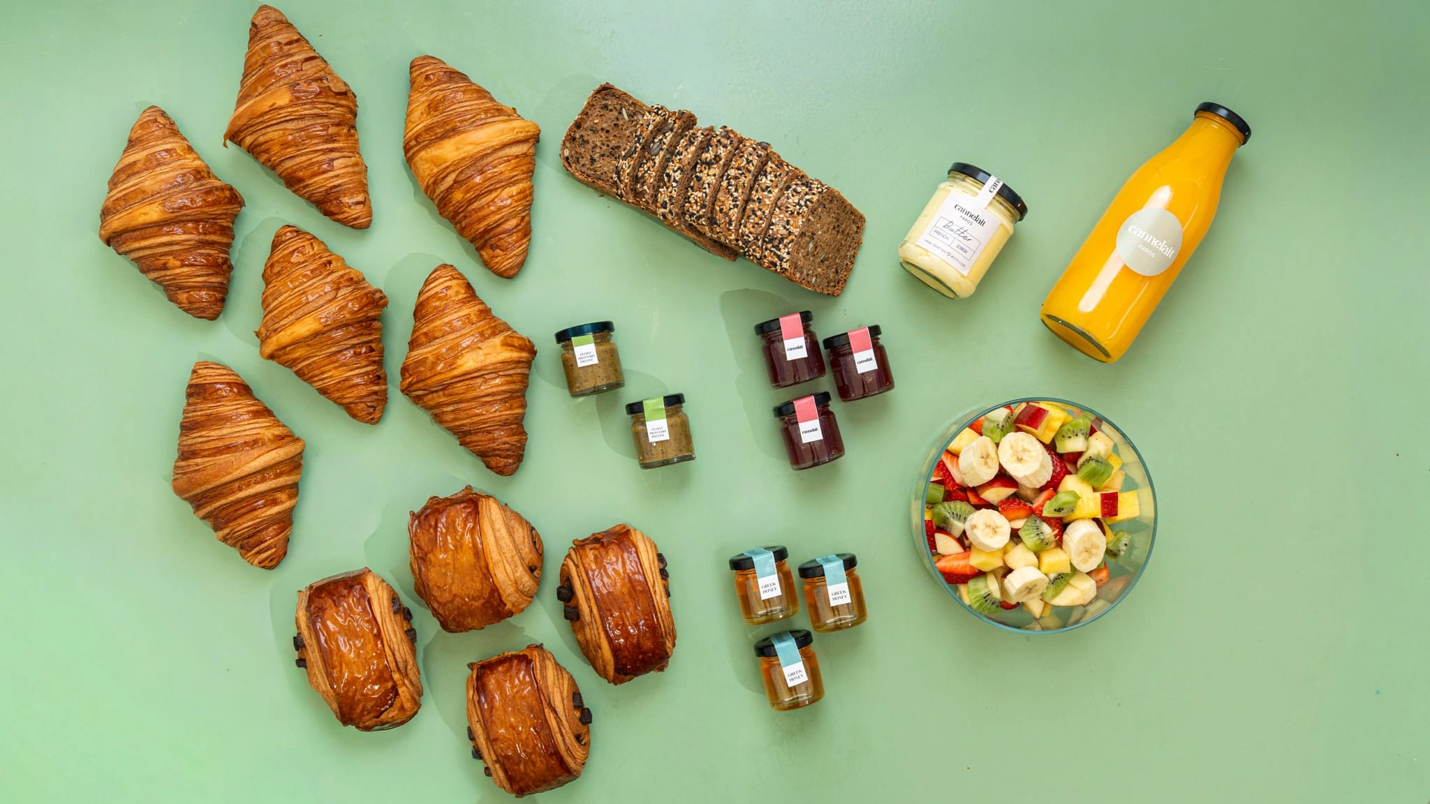 viennoiserie feast with croissants, pain au chocolat, bread, jams and fruit salad